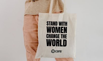 A person holding a tote bag with the slogan 'Stand with women change the world'
