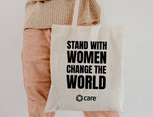 A person holding a tote bag with the slogan 'Stand with women change the world'
