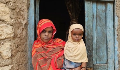 A mother holds a baby in a doorway