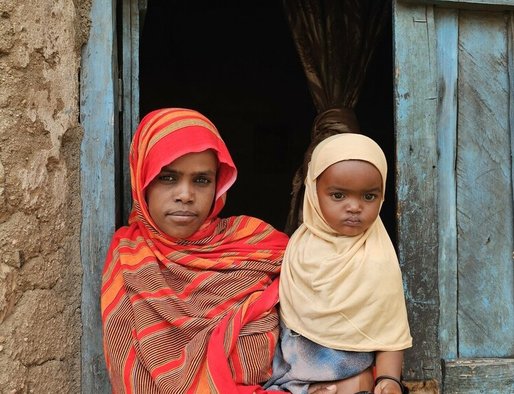 A mother holds a baby in a doorway