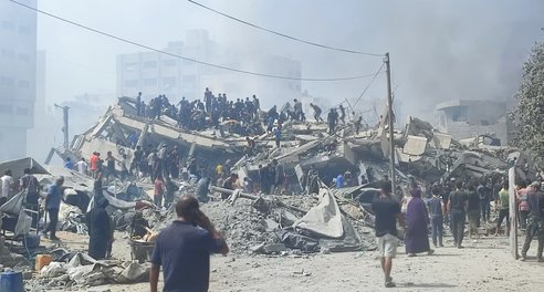 Hundreds of people gather to look for survivors amidst the rubble of a destroyed building in Gaza