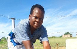 A woman washes her hands under an outdoor tap