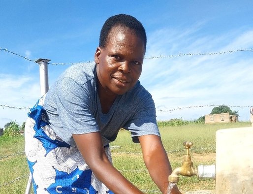 A woman washes her hands under an outdoor tap