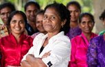 A woman stands confidently with her arms folded in front of a group of women