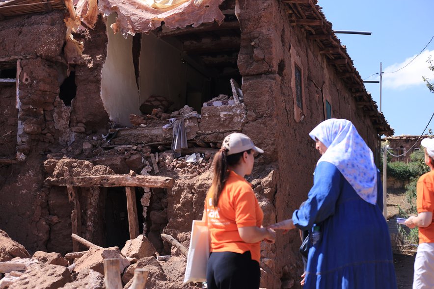 Fatiha talks to CARE staff in front of her collapsed home