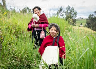 An older women and a young girl stand smiling together in a field