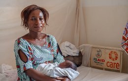 Woman from Kenya sat in a white hospital bed in a CARE Health Centre