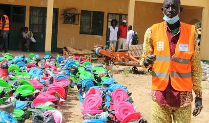 A man in a CARE vest stands next to rows of emergency supplies