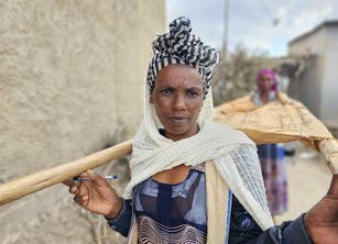 Kahsa holds two sticks supporting a sack for transporting women to medical services