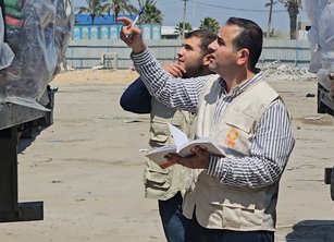 Two humanitarian workers stand by an aid trucker looking at its contents