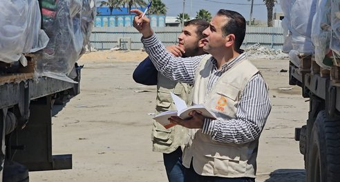 Two humanitarian workers stand by an aid trucker looking at its contents