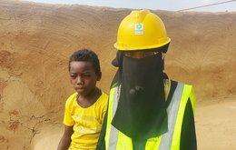 A woman and small boy stand by a dusty building site