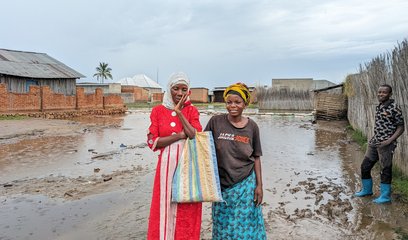Two women stand in front of flooded homes