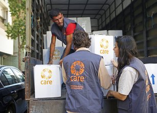 Three CARE staff unload boxes of humanitarian aid from a truck