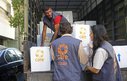 Three CARE staff unload boxes of humanitarian aid from a truck