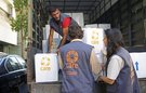 Three CARE staff unload boxes of humanitarian aid from a truck