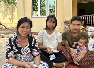 A family of four sit on a mat on the floor