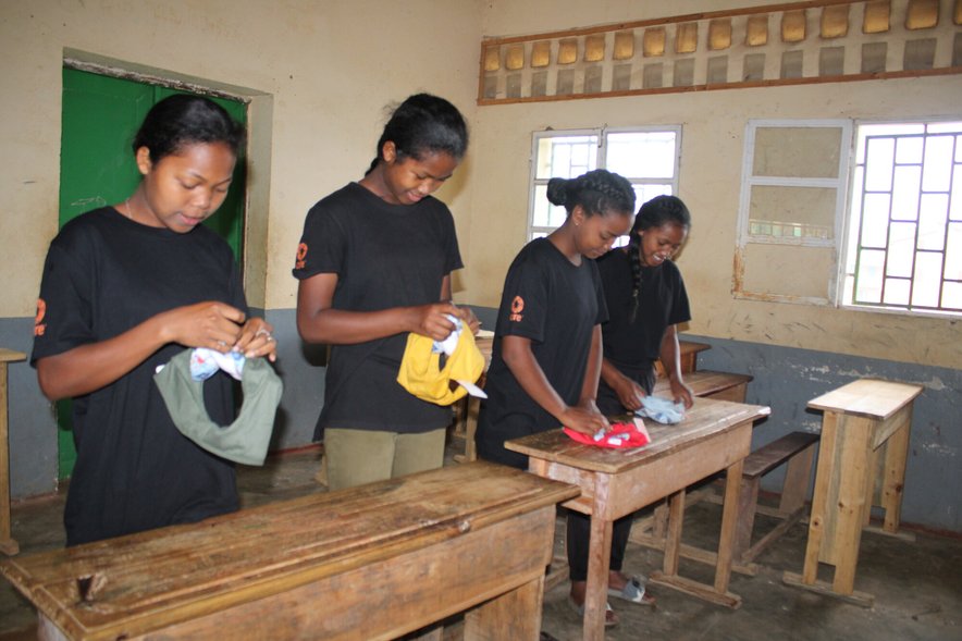 Four school girls in a classroom holding hand-made period products