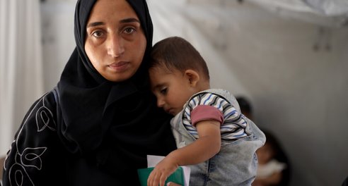 A mother holds a baby close to her chest