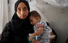 A mother holds a baby close to her chest