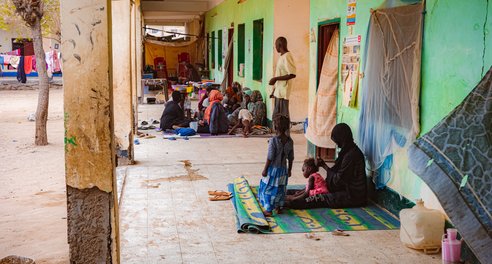 Groups of women and children sit on the floor together in an IDP camp in Port Sudan