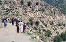 A group of people walking along a road cutting through mountains
