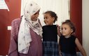 A woman and two young girls smile at each other in a hospital clinic room