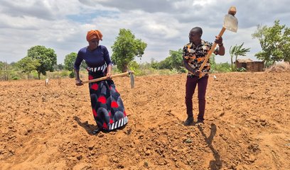 A woman and a man farming some very dry land