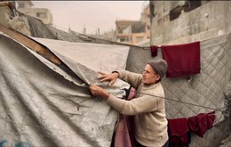 A man makes reparis to a tent