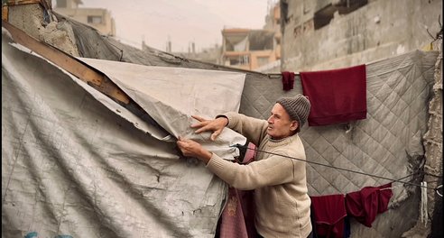 A man makes reparis to a tent