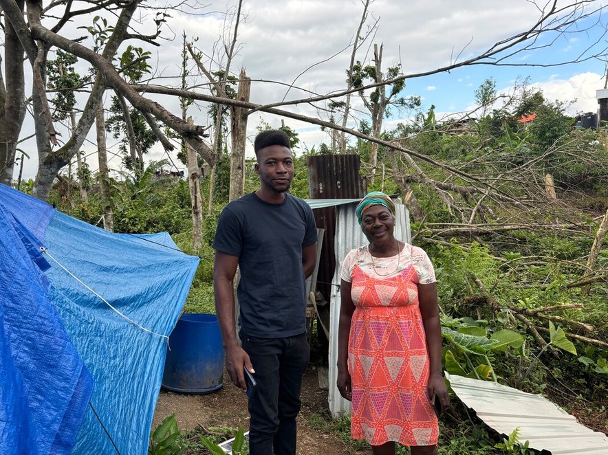 A woman and her son stand together by a temporary shelter