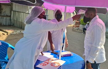 Two healthcare workers in masks conduct temperature checks