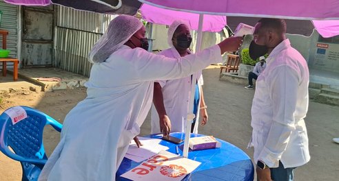 Two healthcare workers in masks conduct temperature checks