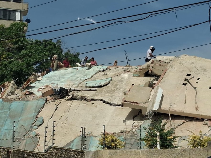A person walks across the top of the rubble of a destroyed building