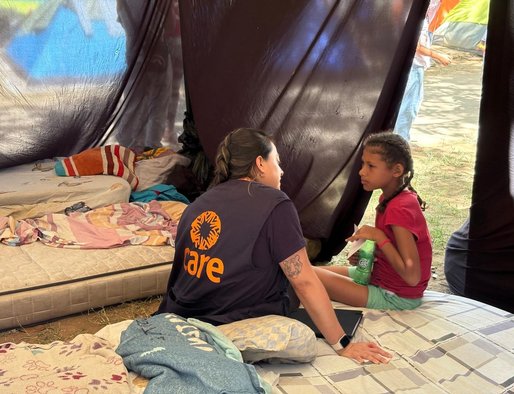 A CARE team member talks with a young girl inside a tent