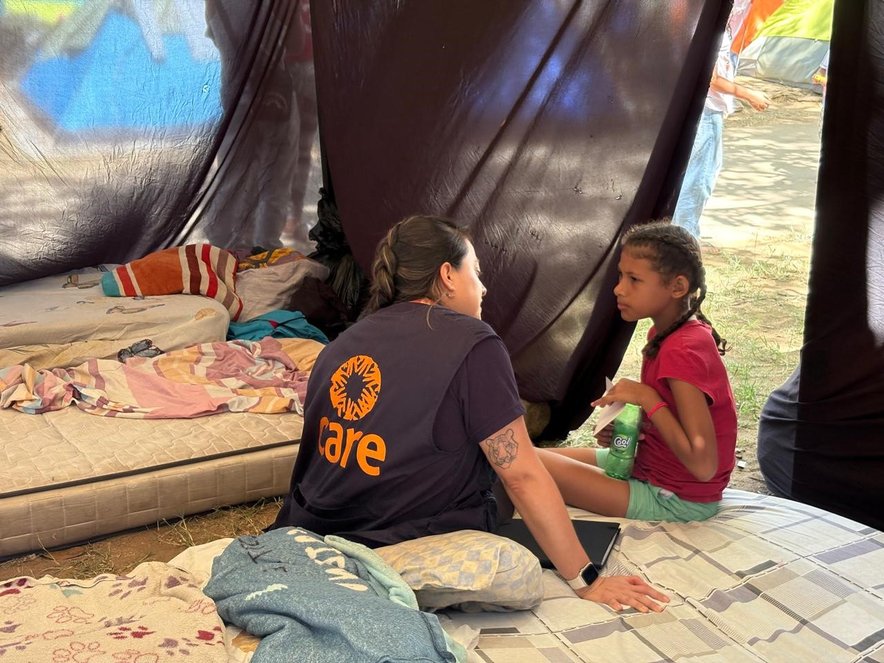 A CARE team member talks with a young girl inside a tent