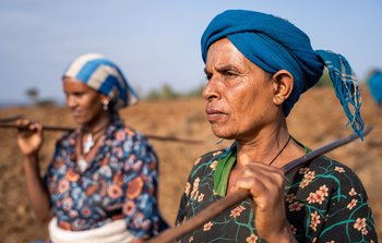 Two women carry their tools as they prepare to work farmland in Ethiopia