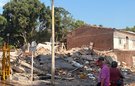 Two people look at the rubble of a building destroyed by an earthquake