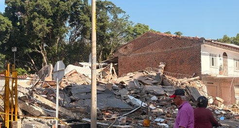 Two people look at the rubble of a building destroyed by an earthquake