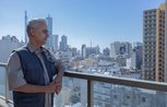 A man looks out over a view of Lebanon from a rooftop balcony