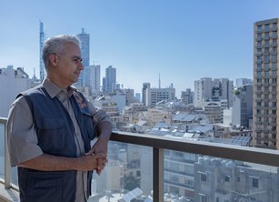 A man looks out over a view of Lebanon from a rooftop balcony