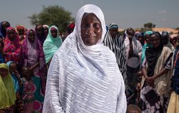 A group of women in a dry landscape, a woman in a white headscarf is in the foreground