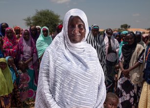 A group of women in a dry landscape, a woman in a white headscarf is in the foreground