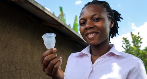 A young woman holding a menstrual cup
