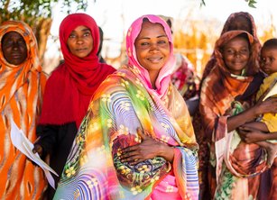 A woman stands at the front of a group of women with her arms folded