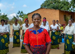 A woman in a bright red blouse standing in front of a group of women