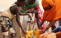 Women and children are filling up water tanks in an internally displaced persons camp in Somalia.