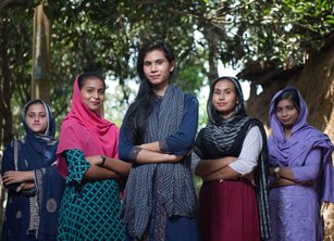 A group women stand with their arms folded in a triangle formation