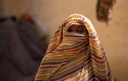 A woman wearing a headscarf looks to camera, only her eyes are visible