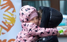 A woman hugs a young girl